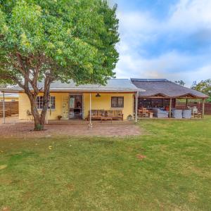 a yellow house with a tree in the yard at THE LAZY LAPA in Magaliesburg