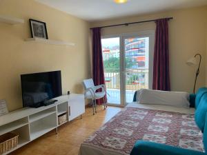 a living room with a television and a large window at Apartamentos Turísticos Yamasol in Fuengirola