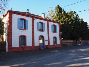 a red and white building on the side of a street at La Gare De Millas Chambres d'hôtes in Millas