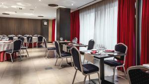 a dining room with tables and chairs and red curtains at Be Live City Center Talavera in Talavera de la Reina