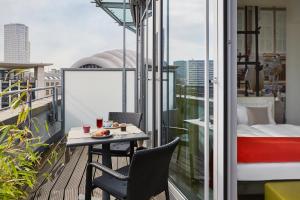einen Balkon mit einem Tisch, Stühlen und einem Bett in der Unterkunft Hotel Indigo Berlin – Ku’damm, an IHG Hotel in Berlin