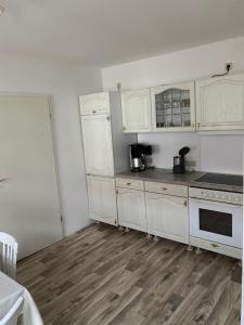 a kitchen with white cabinets and a wooden floor at Ferienwohnung Etgersleben in Etgersleben