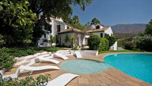 una piscina con sillas blancas y una casa en Casa Bourani, en Casares