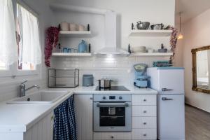 a kitchen with white cabinets and a sink and a refrigerator at Maison Triantatria in Plaka Milou