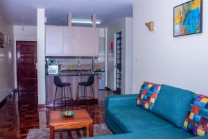 a living room with a blue couch and a kitchen at Kasty M Apartments- W Place in Nairobi