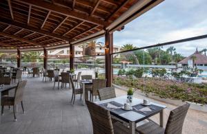 una zona de comedor al aire libre con mesas y sillas en Los Zocos Impressive Lanzarote en Costa Teguise