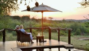 duas pessoas sentadas num convés com um guarda-chuva em Motswiri Private Safari Lodge em Madikwe Game Reserve