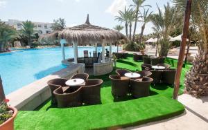 a group of tables and chairs next to a pool at Djerba Resort- Families and Couples Only in Djerba