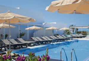 a swimming pool with chairs and umbrellas at Riu La Mola in Playa Migjorn