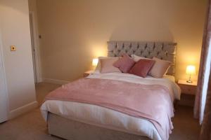 a bedroom with a large bed with pink sheets and pillows at Mostyn Villa 2 in Llandudno