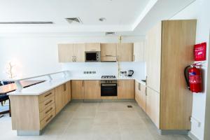 a kitchen with wooden cabinets and a red fire extinguisher at Waterfront Hotel Apartment in Lusail