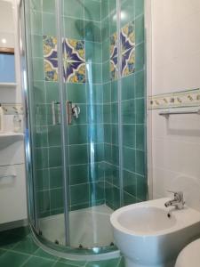 La salle de bains est pourvue de carrelage vert, d'un lavabo et d'une douche. dans l'établissement B&B Ap, à Piano di Sorrento