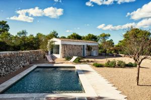 a pool in the backyard of a house with a stone wall at Menorca Experimental in Alaior