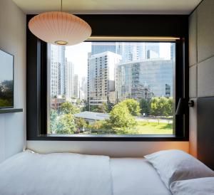 een slaapkamer met een raam met uitzicht op de stad bij citizenM Seattle South Lake Union in Seattle