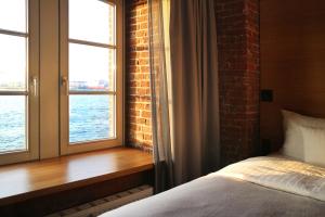 ein Schlafzimmer mit einem Bett und zwei Fenstern mit Wasser in der Unterkunft GINN Hotel Hamburg Elbspeicher in Hamburg