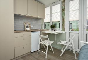 a kitchen with white cabinets and white chairs in a room at Anna Green House in Palanga +23 photos