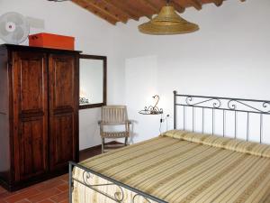 een slaapkamer met een bed, een kast en een stoel bij Holiday Home L'Uccelliera by Interhome in Il Prato
