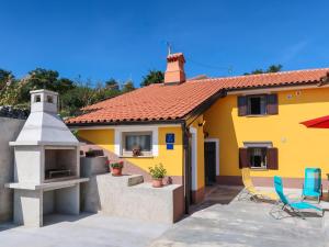 a yellow house with a porch and chairs at Holiday Home Elija by Interhome in Mošćenička Draga
