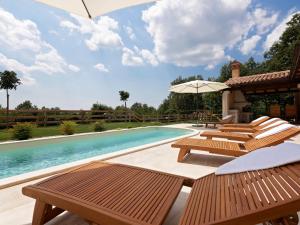 een zwembad met houten stoelen en een zwembadvisorvisor bij Villa Lucija by Interhome in Pazin
