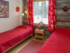 two beds in a room with red sheets and a window at Holiday Home Lumipolku a 1 by Interhome in Äkäslompolo +15 photos