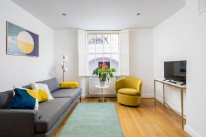 ein Wohnzimmer mit einem grauen Sofa und einem gelben Stuhl in der Unterkunft Chic and modern 2-bed flat with patio in Pimlico, Central London in London