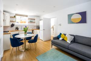 ein Wohnzimmer mit einem Sofa, einem Tisch und Stühlen in der Unterkunft Chic and modern 2-bed flat with patio in Pimlico, Central London in London