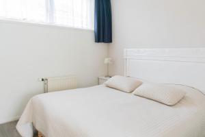 ein weißes Bett in einem weißen Schlafzimmer mit einem Fenster in der Unterkunft Hotel Lemmer in Lemmer