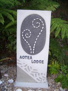 um sinal para um alojamento de turismo selvagem em frente às plantas em Aotea Lodge Great Barrier em Tryphena