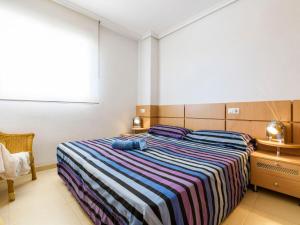 1 dormitorio con 1 cama grande con manta a rayas en Apartment Cala Blanca II - 1ª Linea Frontal-1 by Interhome, en Oropesa del Mar