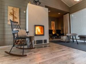a fireplace in a living room with a chair and a fire place at Holiday Home Loma-saaga 3 by Interhome in Syöte
