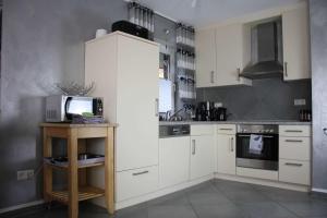 a kitchen with white cabinets and a microwave at Ferienhaus Nordseeperle in Hooksiel