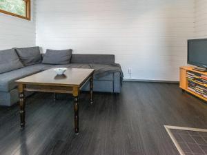 a living room with a couch and a table and a tv at Holiday Home Hiekkalahti by Interhome in Sastamala
