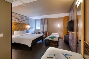 a hotel room with two beds and a television at ibis Zürich City West in Zurich