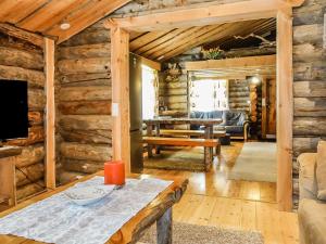 Cabaña de madera con sala de estar con mesa y TV. en Holiday Home Kelokota by Interhome, en Salla