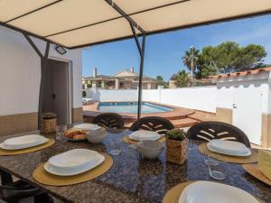 a dining table with chairs and a table umbrella at Holiday Home Estrella by Interhome in Riumar +31 photos