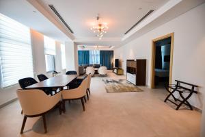 a dining room with a table and chairs and a living room at Waterfront Hotel Apartment in Lusail