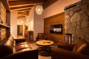 a living room with leather furniture and a stone wall at DaSus Lux&Wellness Apartments Sosana in Demanovska Dolina