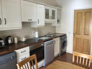 cocina con armarios blancos, fregadero y lavavajillas en Dobbin Lodge, en Armagh