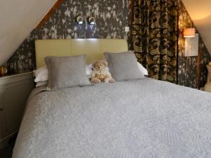 a teddy bear sitting on top of a bed at Chequer Cottage in Horseheath