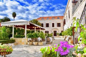 a patio with a white umbrella and some flowers at Boutique Hotel Kazbek in Dubrovnik