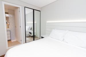een slaapkamer met een wit bed en een spiegel bij Multihouse - Moderno Duplex Berrini - WTC - Brooklin in Sao Paulo
