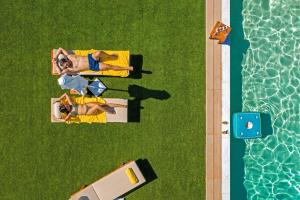 a group of people standing next to a swimming pool at Villa Artemida Vravrona in Vravrona