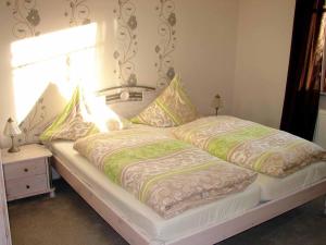 a bed with two pillows on it with a window at Ferienwohnung Stirnbergblick in Ehrenberg