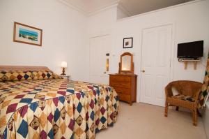 een slaapkamer met een bed, een dressoir en een tv bij Kilmichael House in Drumnadrochit +53 foto's