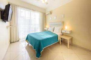 um quarto com uma cama com um cobertor azul e uma televisão em Hotel Shakey em Santo Domingo