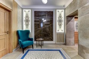 La salle de bains est pourvue d'une chaise bleue et d'une porte en verre. dans l'établissement Arbat Nord Hotel, à Saint-Pétersbourg