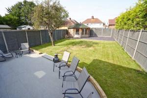 a patio with chairs and a yard with a fence at Home from home - 4 Double Bed House with Parking in Slough