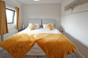 a bedroom with a bed with a yellow blanket on it at Home from home - 4 Double Bed House with Parking in Slough