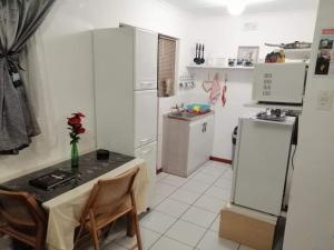 a kitchen with white appliances and a table and chairs at Garden Route Stay in George