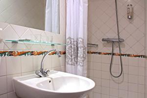 La salle de bains blanche est pourvue d'un lavabo et d'une douche. dans l'établissement Hôtel de l'Amphithéâtre, à Arles